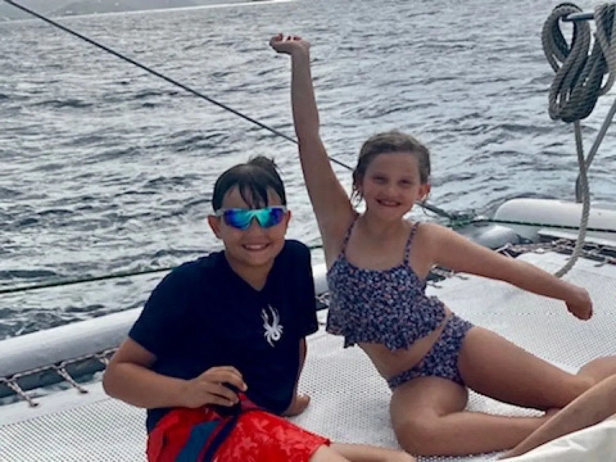 a group of young children sitting next to a body of water